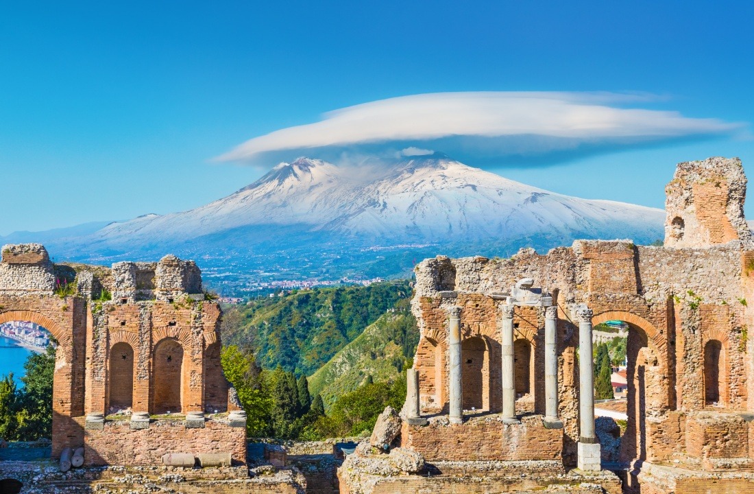 Ancient Greek theatre in Taormina on background of Etna Volcano, Sicily, Italy.